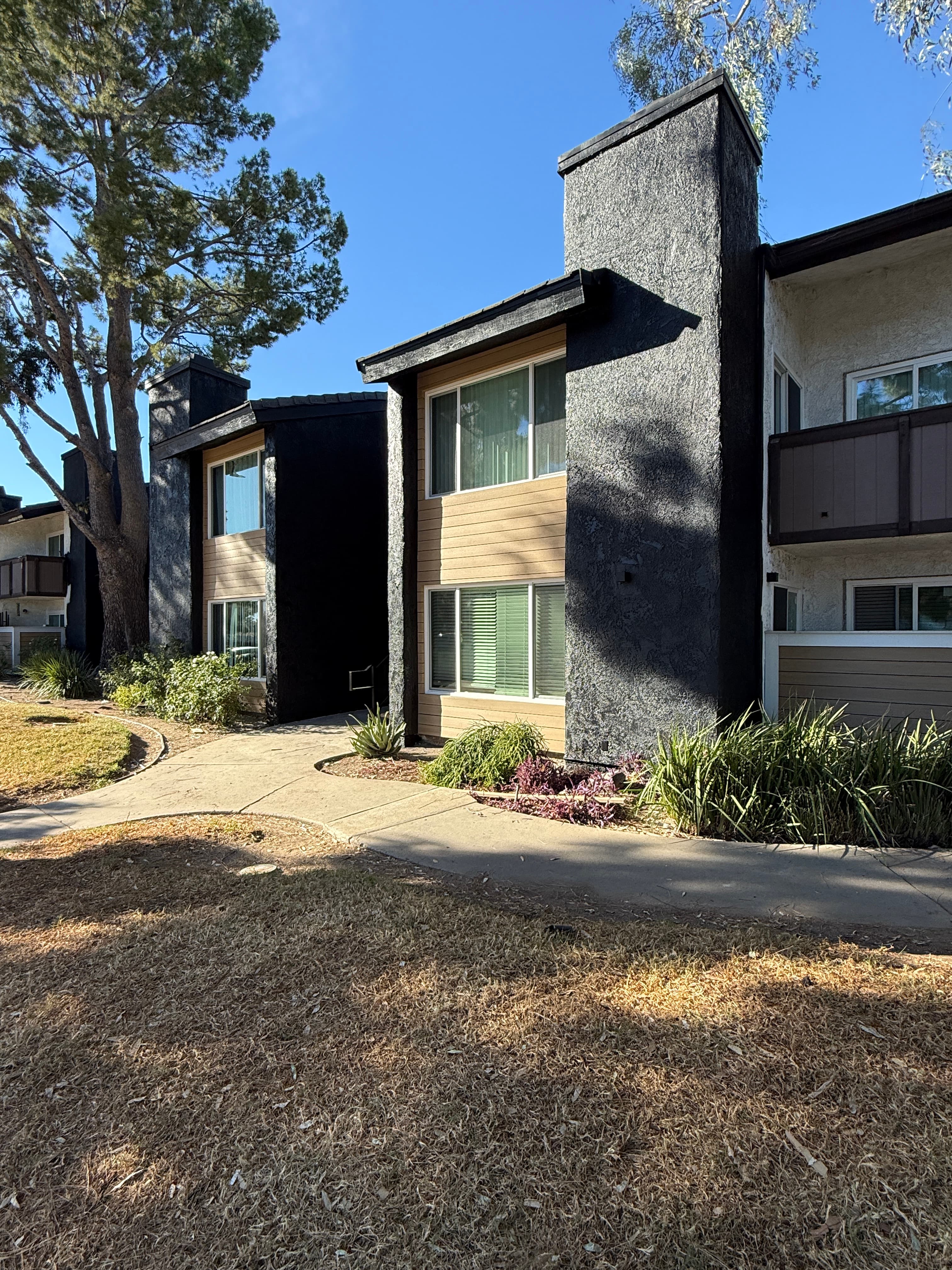 Multifamily building exterior with charcoal stucco accents, horizontal siding, and white windows
