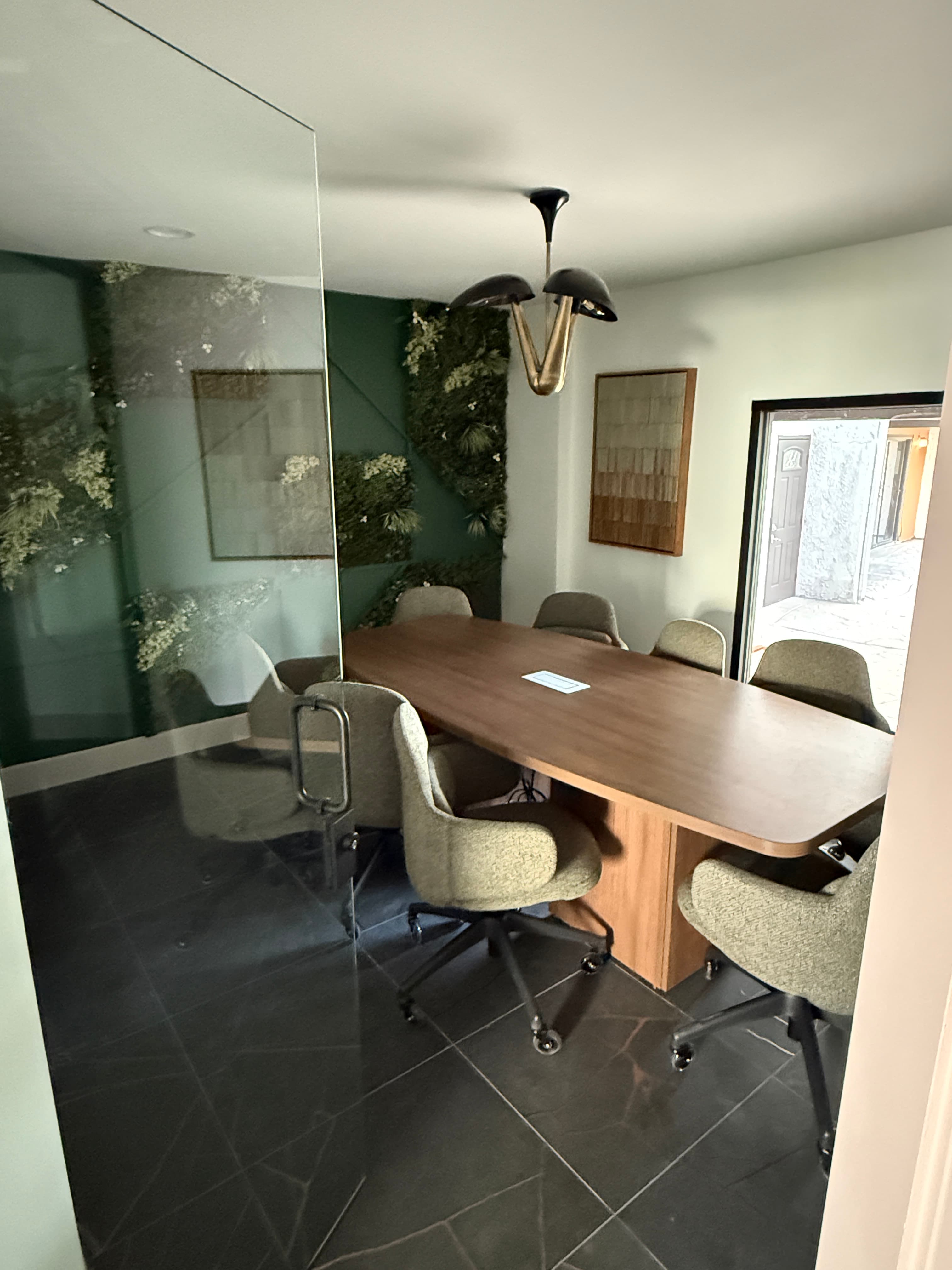 Leasing office meeting room with glass partitions, a wood table, and green feature wall