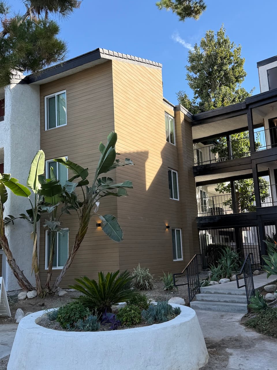 Three-story apartment exterior showing siding, windows, railings, and shared walkways